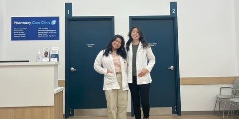 Two co-op students smiling in white coats