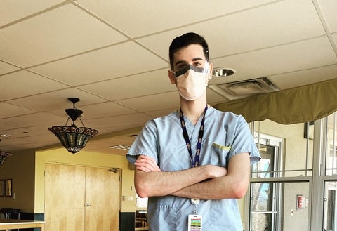 Brad Murphy in scrubs and a mask with his arms crossed