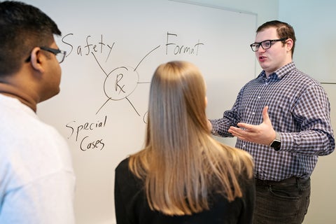 Image of a graduate student teaching assistant talking with PharmD students