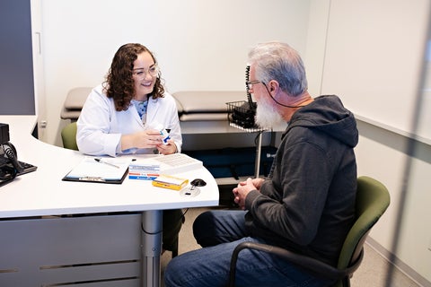 A female pharmacist holding a prescription box consulting with a patient
