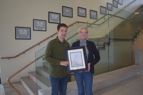 Paul Malik smiling next to Dr. Andrea holding an award. 