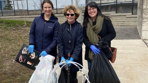 Three women holding garbage and garbage bags