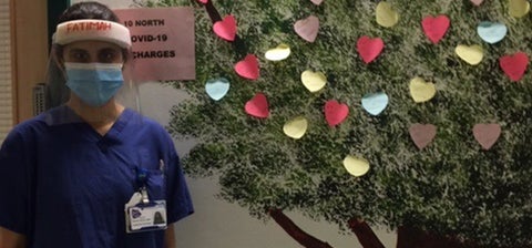 Fatimah standing next to a painted tree mural with butterflies on it