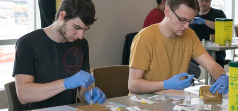 Two students preparing needles for vaccinations in a workshop