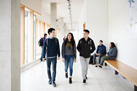 three students walking down a hallway at the School of Pharmacy