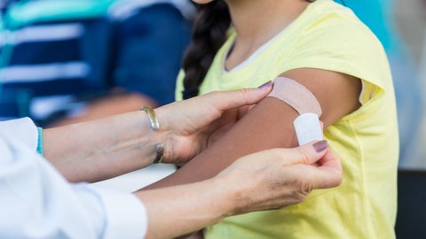 A bandaid being placed on a woman's arm