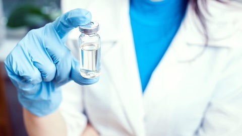 Close up of woman in white pharmacist coat holding a vile