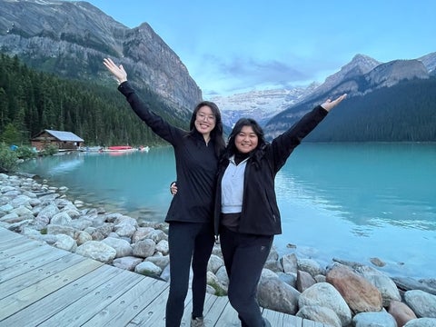 Two co-op students pose infront of mountains and lake smiling