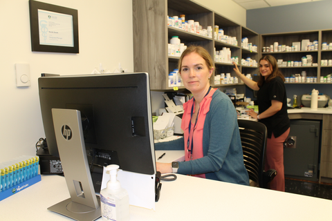 Two people working in a pharmacy and smiling at the camera