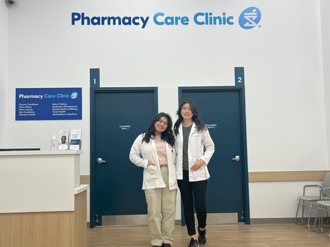Shirley and Melinda wearing white coats, standing in front of Pharmacy Care Clinic