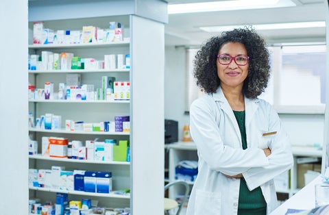 A black woman in a lab coat standing in a pharmacy