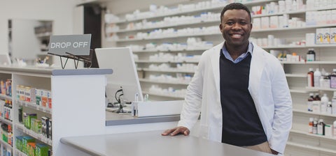 Michael in a lab coat in his pharmacy smiling