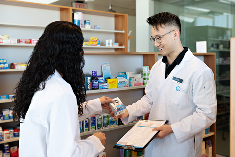 Two people in lab coats talking in pharmacy