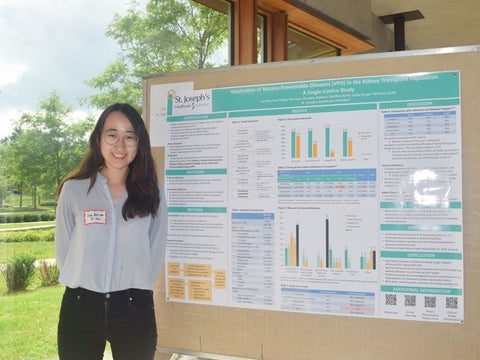 Lisa Ros-Choi standing next to a poster