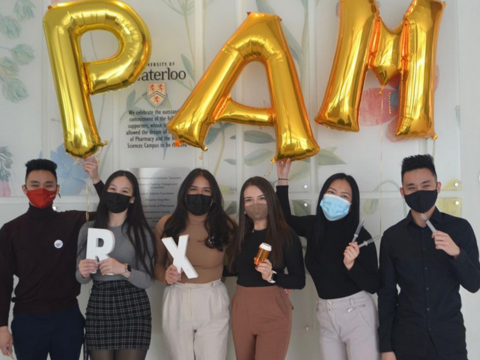 Group of students in masks holidng balloons that spell "PAM"