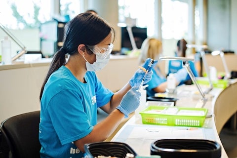 Women wearing medical mask and gloves holding syringe 