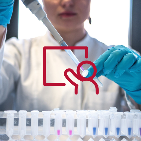 Female scientist pipetting colored chemicals into a tube.