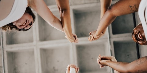 Women with hands interlocked in the air smiling