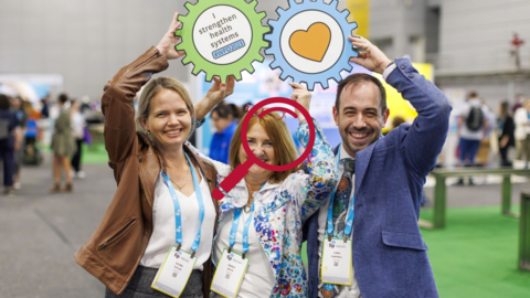 Three people smiling holding gear signs that say I strengthen health systems #WPD2023