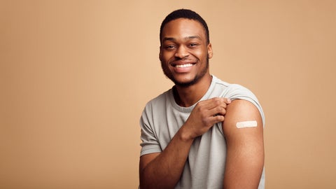 Black man showing bandain on shoulder post vaccine