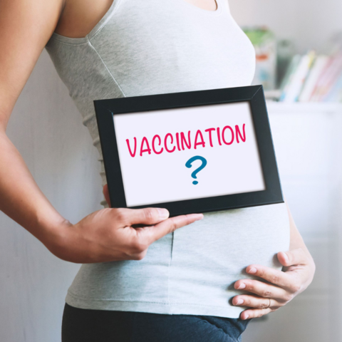 Pregnant woman holding sign that reads "vaccination"