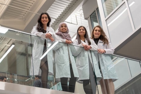 4 PharmD students smiling at camera while standing on balcony