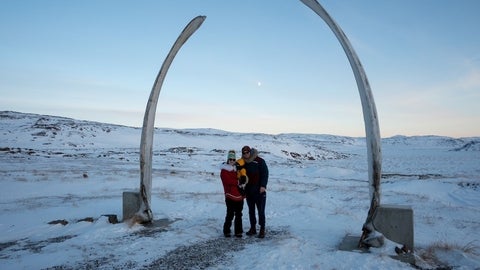 Two people and their child standing in the snow