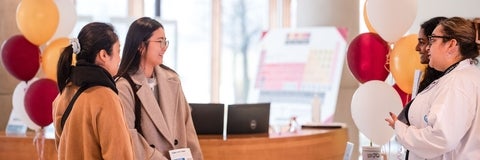 People smiling in conversation with balloons next to them 