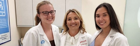 Three women in white coats smiling