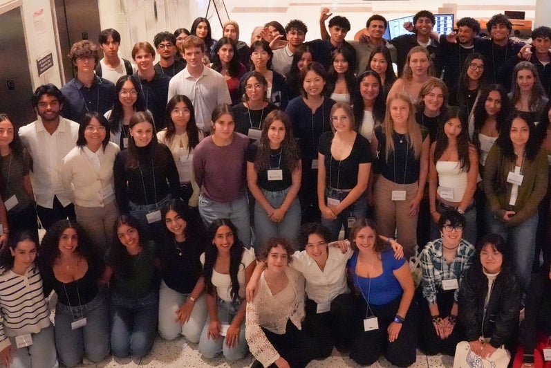 A large group of students smiling in a lobby