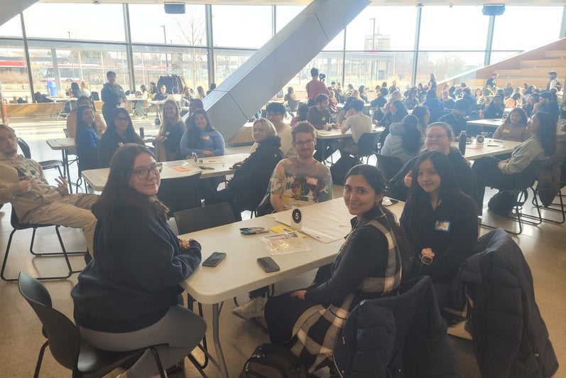 A group of students sitting and smiling around a table