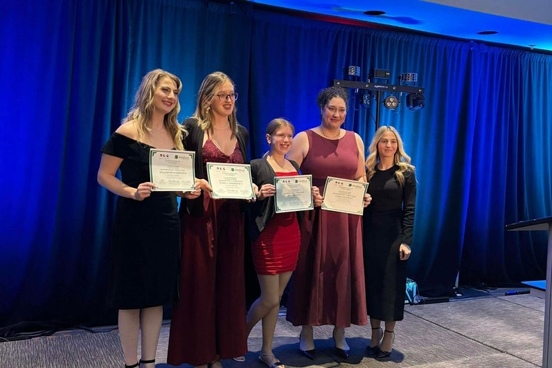 Students smiling holding signs