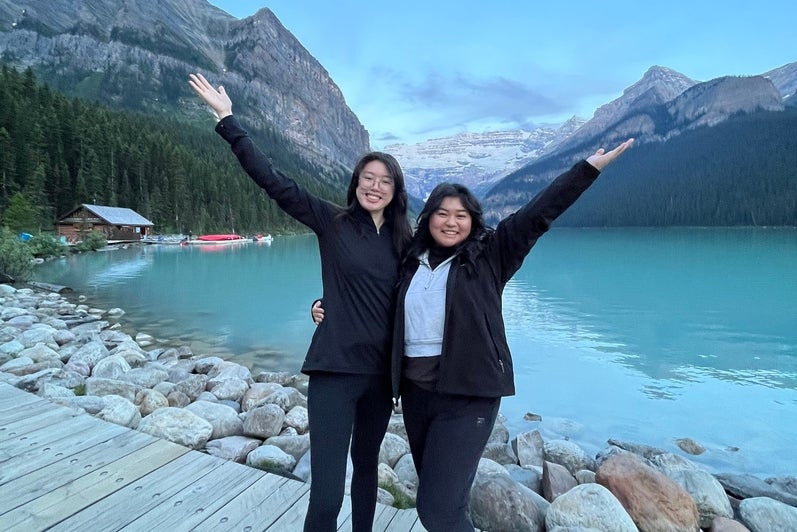 Two co-op students pose infront of mountains and lake smiling