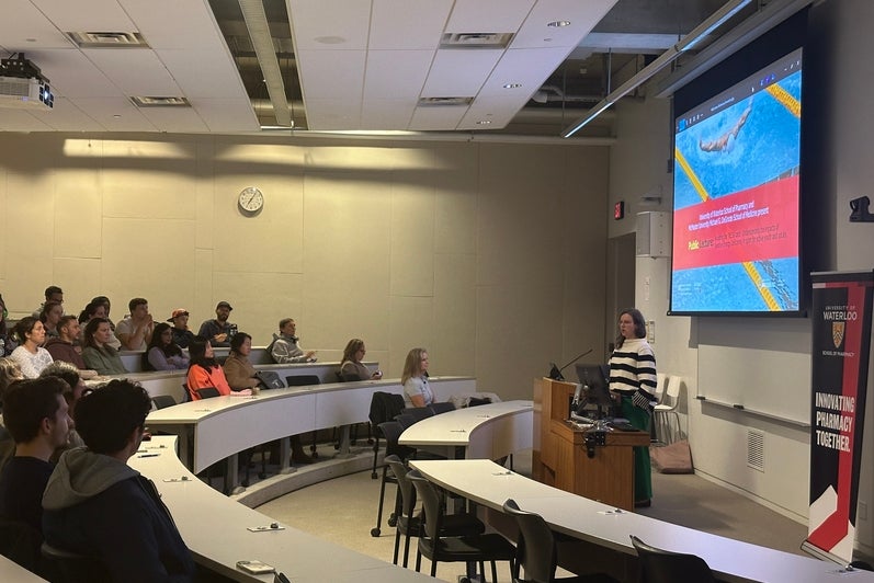A woman giving a lecture to a classroom full of people 