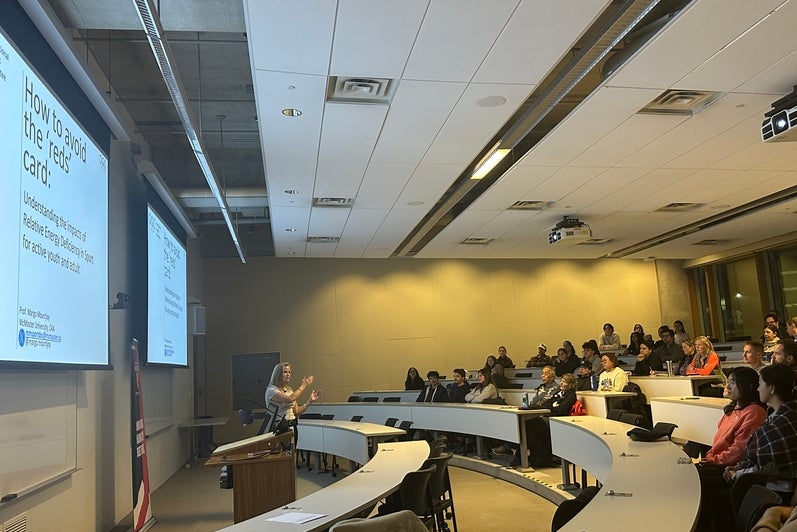 A woman giving a lecture to a classroom full of people 