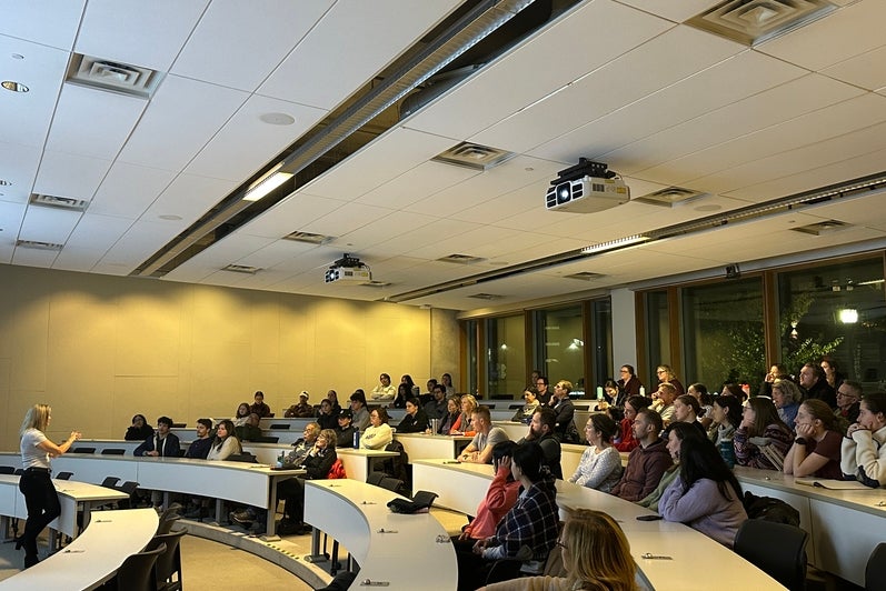 A woman giving a lecture to a classroom full of people 
