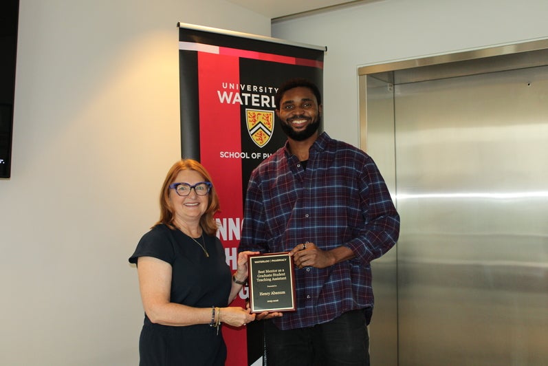 A student holding an award with a faculty member