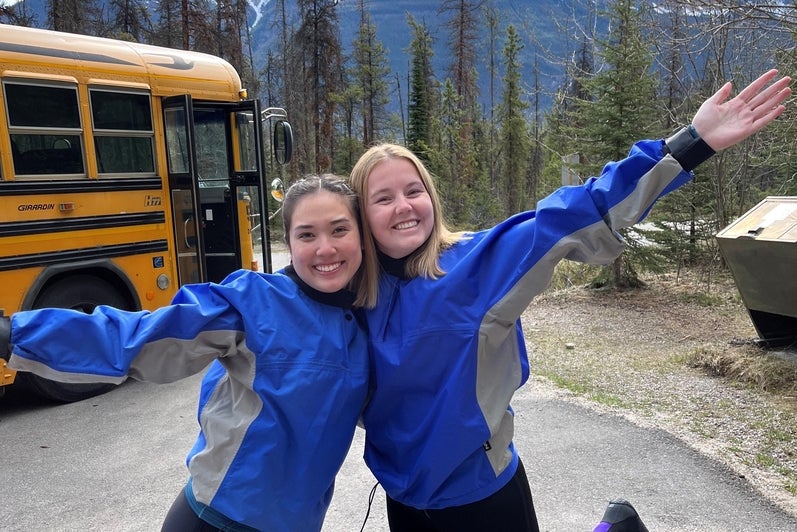 Two women standing smiling in front of mountains