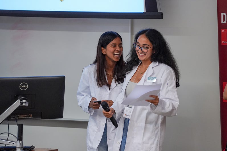 Two students smiling and laughing while presenting