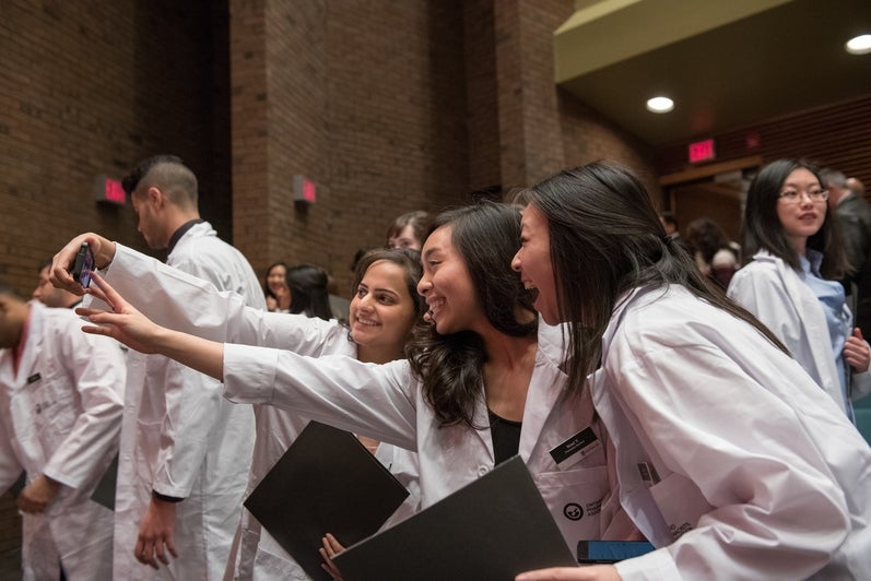 3 students inwhite coats taking a selfie