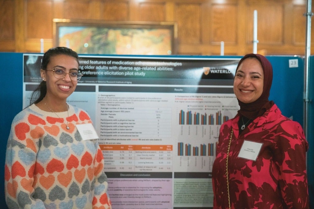 Two graduate students standing next to a poster