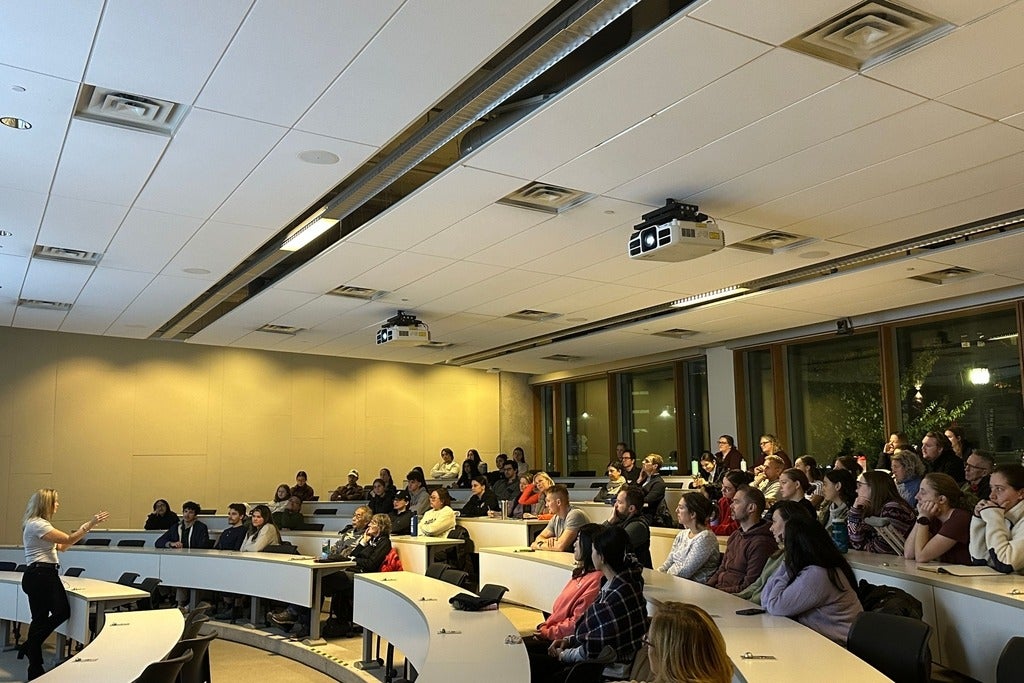 A woman giving a lecture to a classroom full of people 