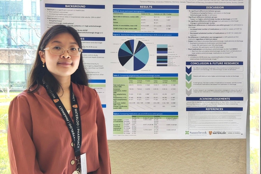 A student smiling standing next to a scientific poster