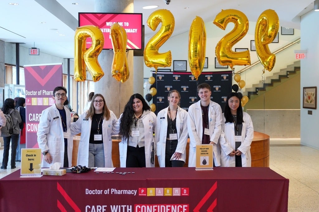 Students smiling standing behind a welcome table