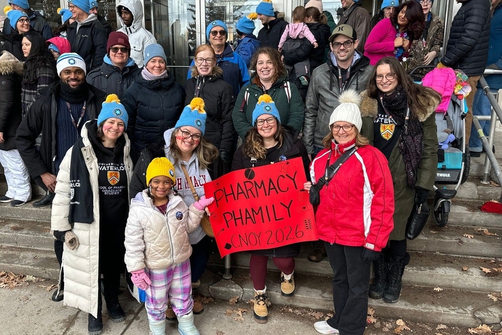 A group of people smiling holding up a sign