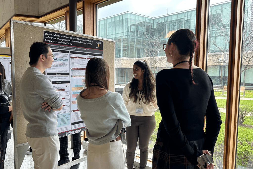 A group of people clustered around a scientific poster listening to a graduate student present