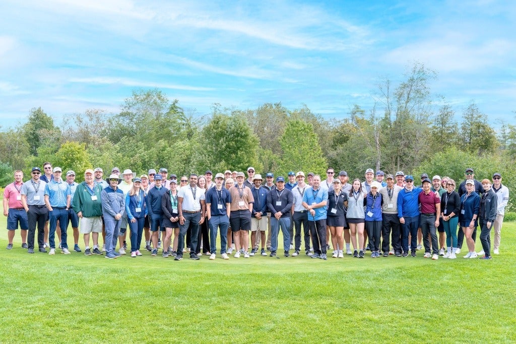 A large group of people standing on the green on a golf course