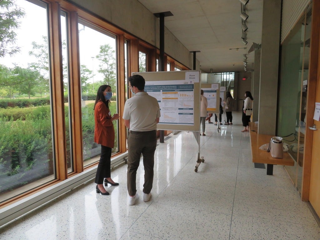 two people standing side by side reading a presentation board