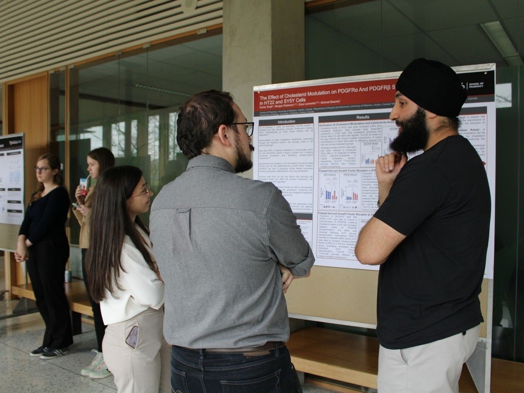 A group pf people standing around a research poster