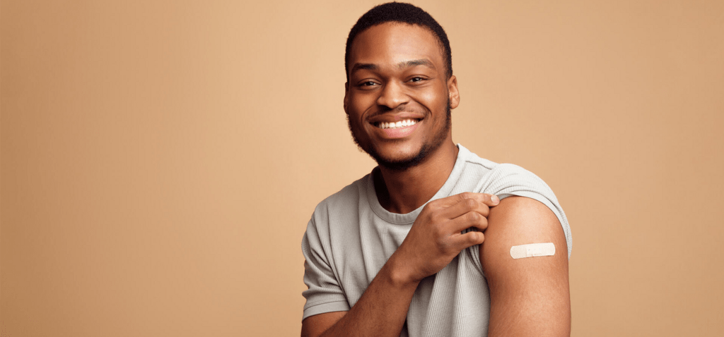 a man rolling up his sleeve and showing a vaccination band-aid